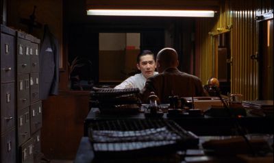 Still from In the Mood For Love (2000) that has been tagged with: night & fluorescent light & over-the-shoulder & medium wide