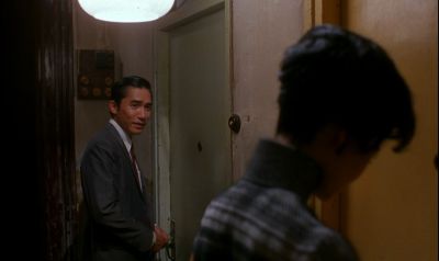 Still from In the Mood For Love (2000) that has been tagged with: over-the-shoulder & door & hallway