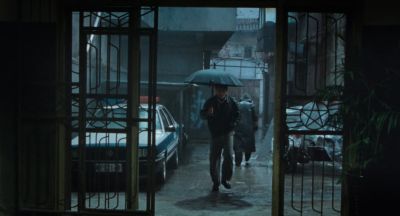 Still from Only the River Flows (2023) that has been tagged with: exterior & day & rain & umbrella