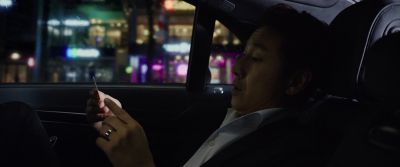 Still from Parasite (2019) that has been tagged with: car interior & car & medium shot & clean single & reading & business card