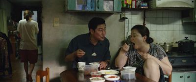 Still from Parasite (2019) that has been tagged with: wide shot & chopsticks & dining room & three-shot