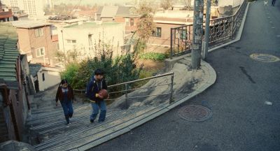 Still from Past Lives (2023) that has been tagged with: two-shot & extreme wide & day & stairs