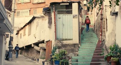 Still from Past Lives (2023) that has been tagged with: two-shot & extreme wide & day & stairs