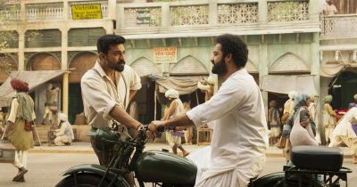 Still from RRR (2022) that has been tagged with: e6be89 & motorcycle & medium wide & two-shot & day