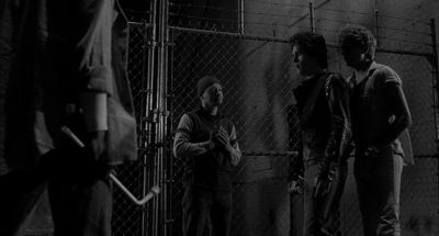 Still from Rumble Fish (1983) that has been tagged with: chainlink fence & night & black and white & group-shot