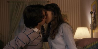 Still from TV Show: Netflix — "Stranger Things: Season 1 - Episode 1" that has been tagged with: night & medium shot & living room & child & kiss & two-shot