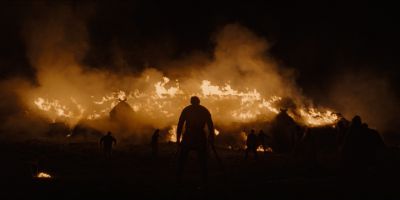 Still from The Northman (2022) that has been tagged with: burning & group-shot & over-the-shoulder & exterior & burning building