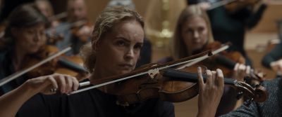 Still from Tár (2022) that has been tagged with: violin & orchestra & medium close-up & interior