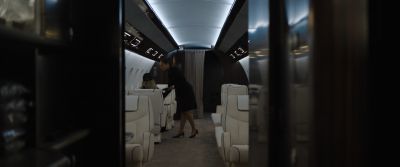 Still from Tár (2022) that has been tagged with: frame in a frame & flight attendant & airplane interior
