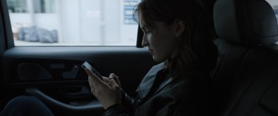 Still from Tár (2022) that has been tagged with: cellphone & medium shot & backseat & clean single & texting